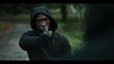 a man in a hoodie aiming a gun