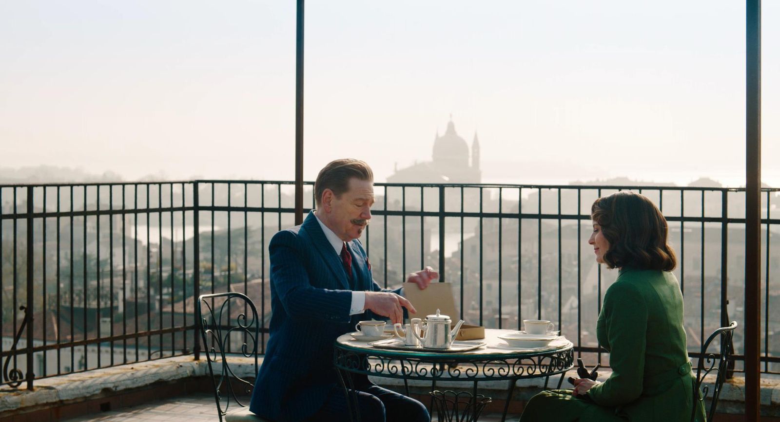 a man and a woman sitting at a table on a balcony