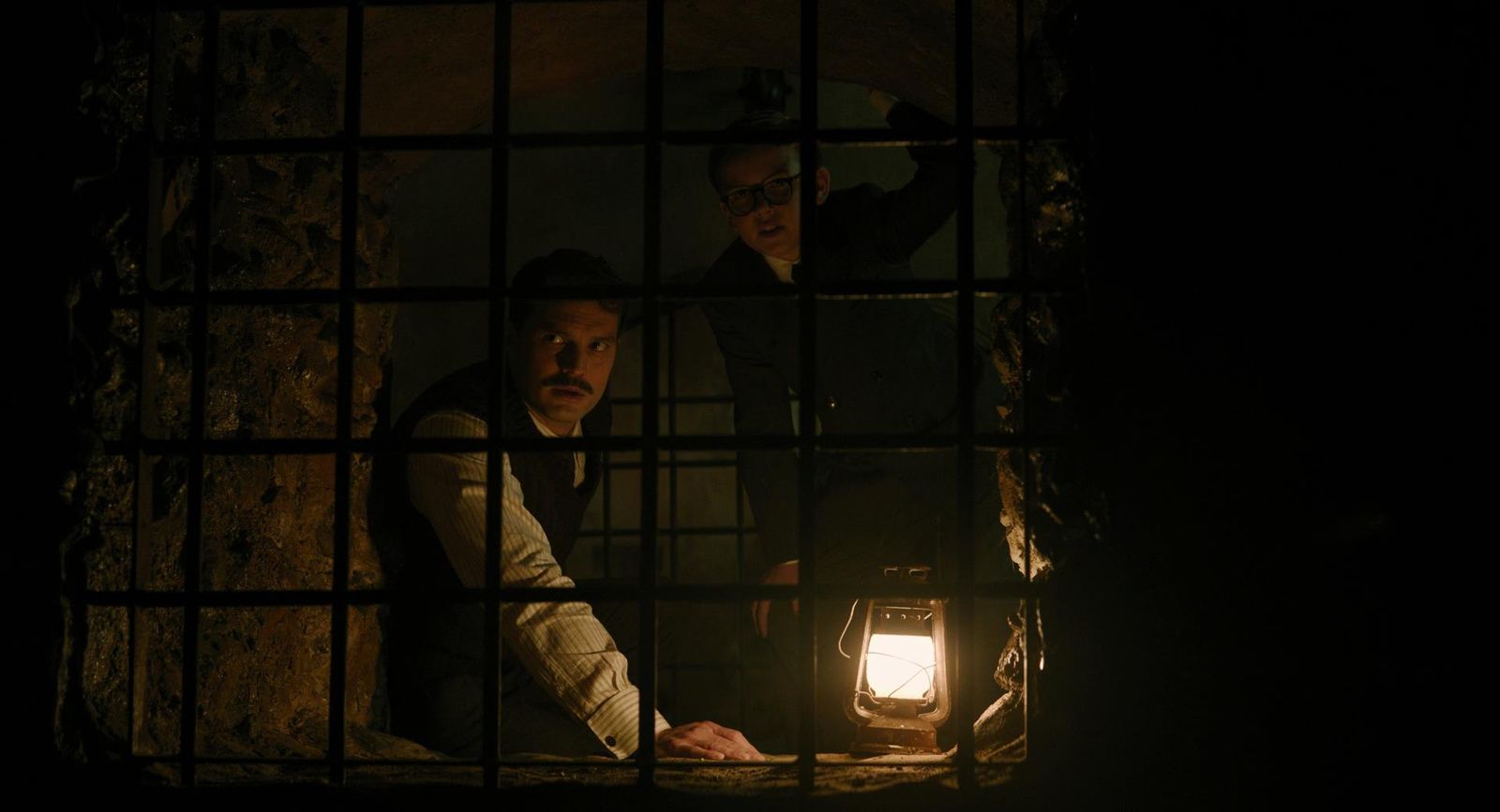 two men in a jail cell with a light on