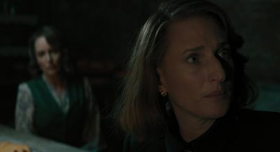 a woman in a dark room with another woman in the background