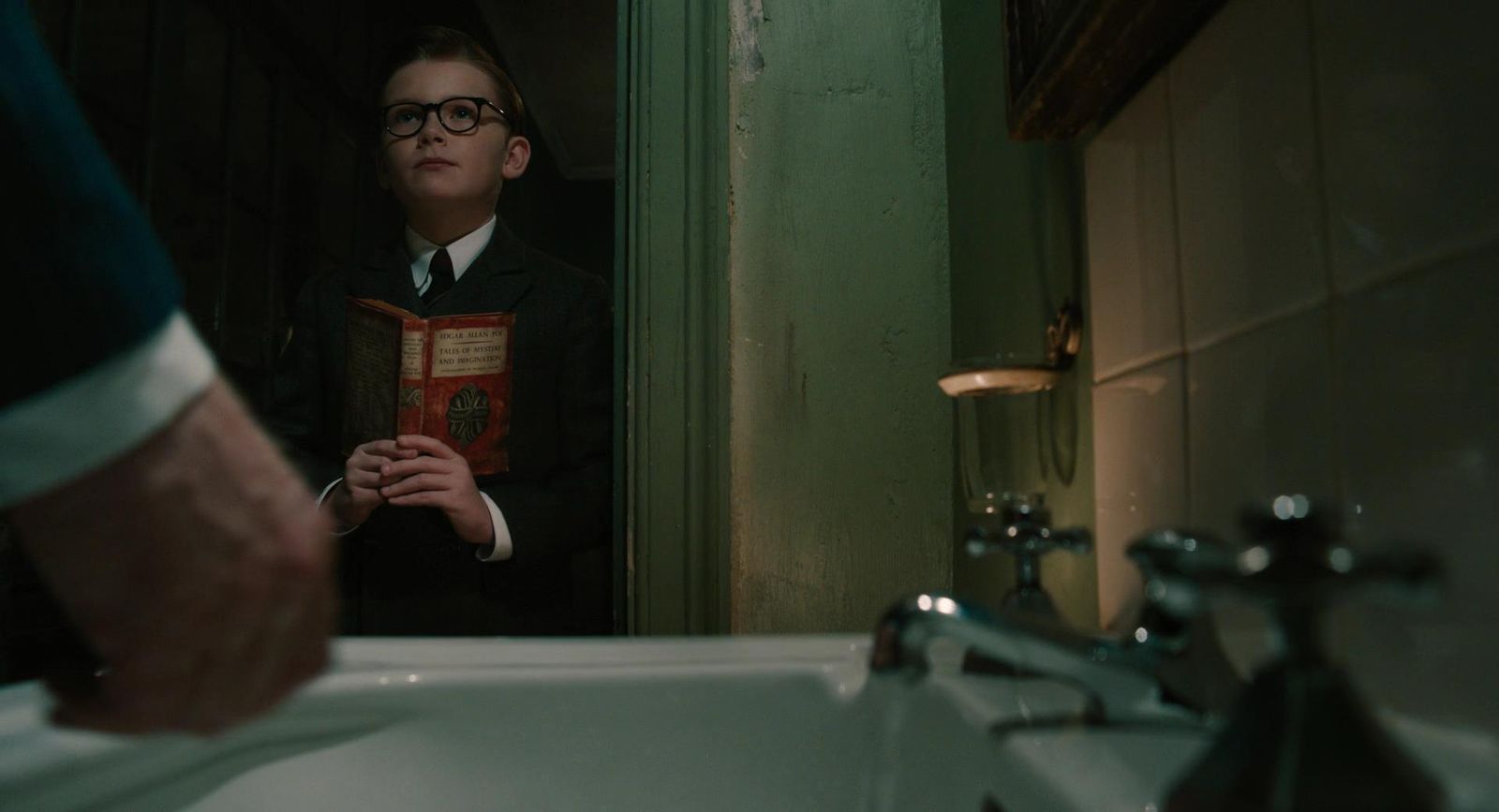 a boy in a suit is holding a book