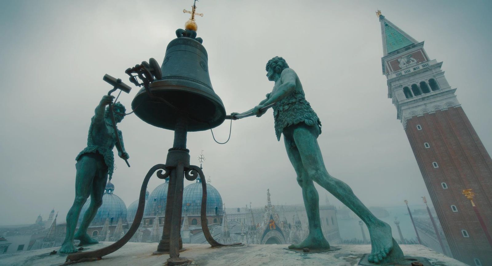 a statue of two men shaking hands next to a bell