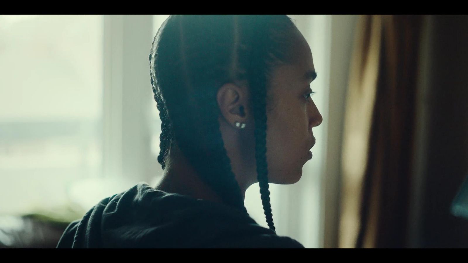 a woman with braids standing in front of a window