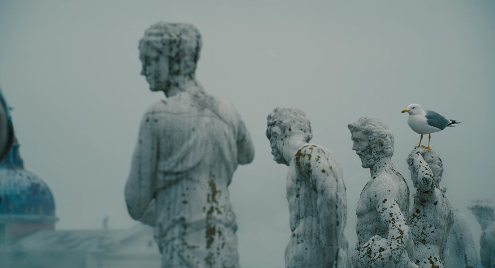 a seagull perched on a statue of a group of people