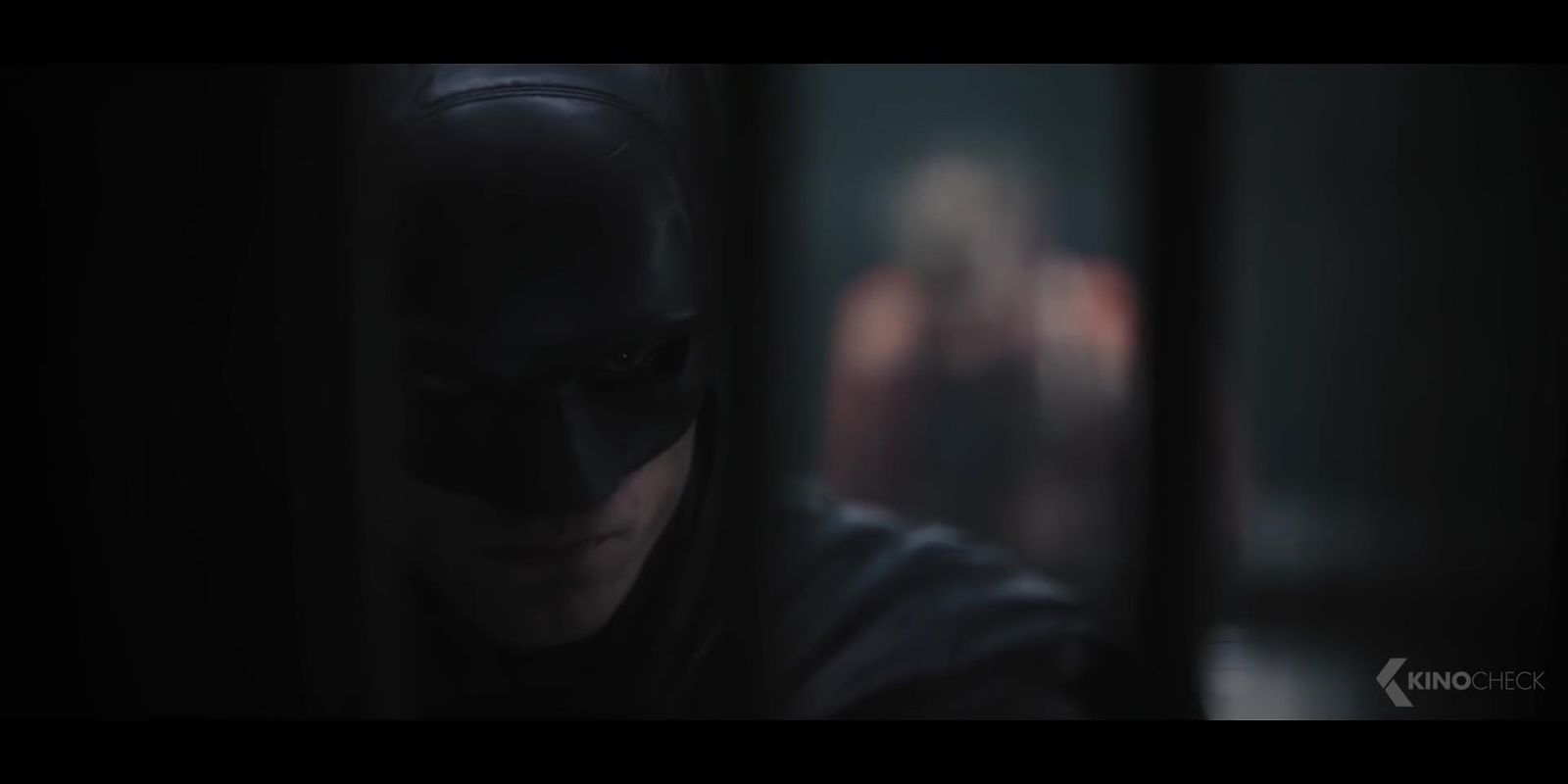 a man in a batman mask looking out of a window