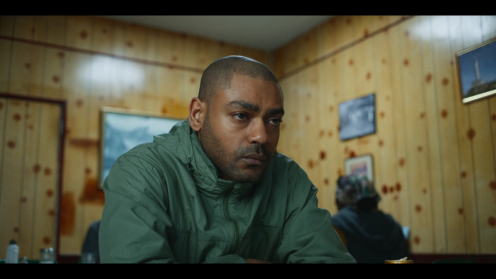 a man in a green jacket sitting in a room