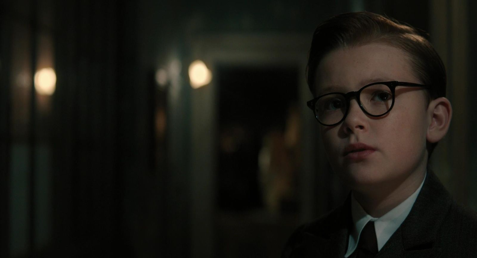 a young boy wearing glasses in a dark room