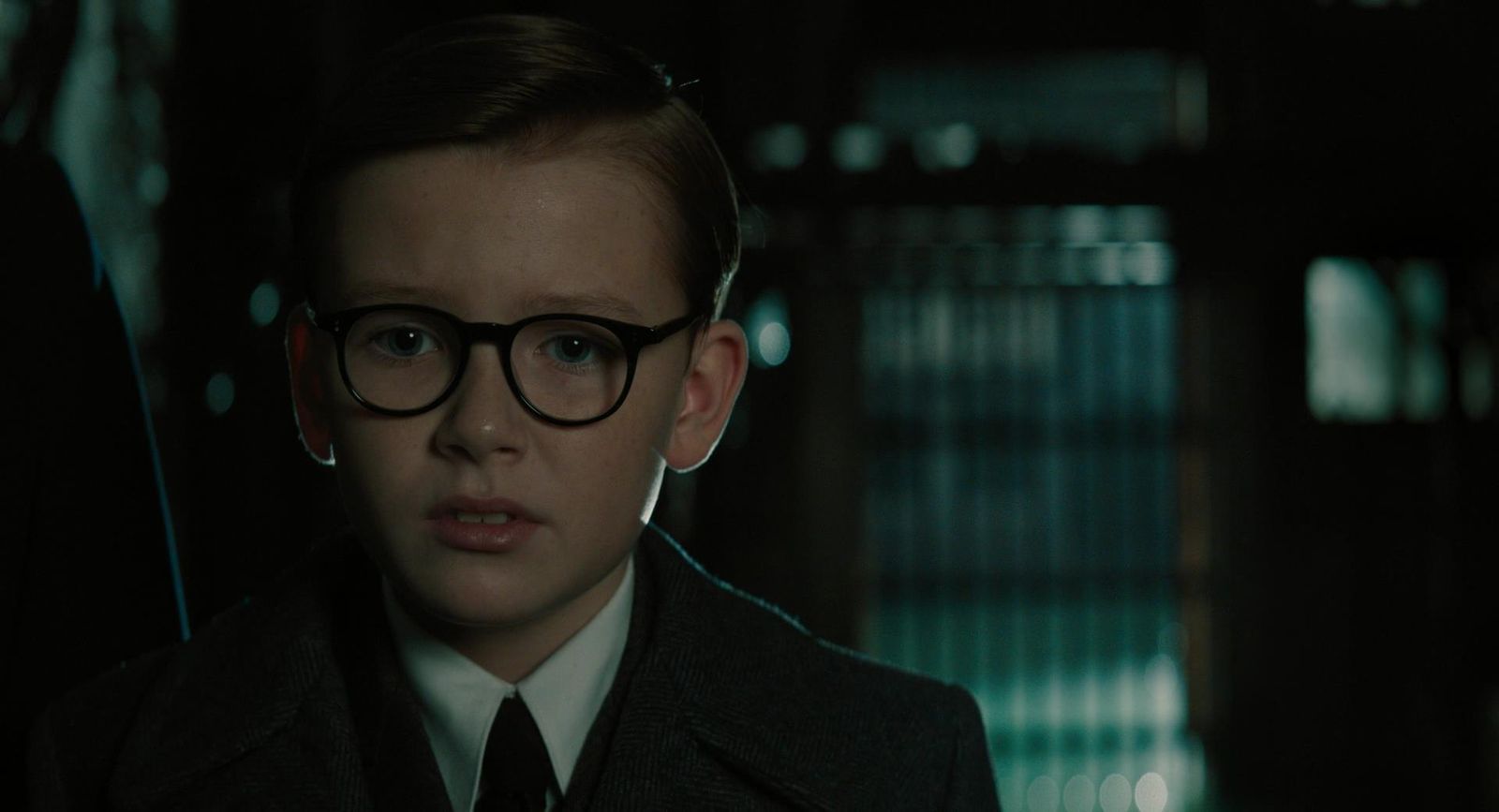 a young boy wearing glasses and a tie