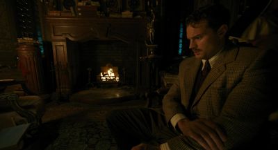 a man in a suit sitting in front of a fire place