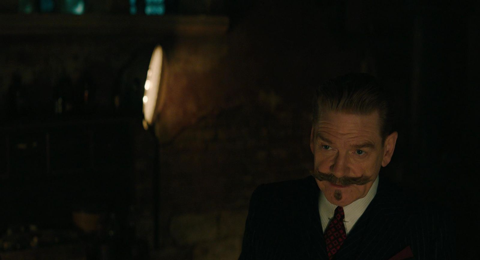 a man with a mustache and a suit in a dark room