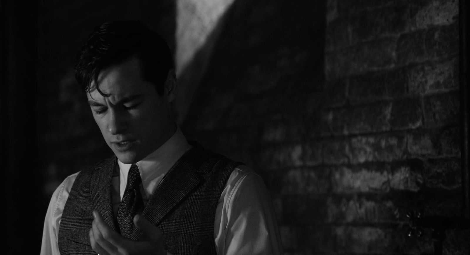 a man in a vest and tie standing in a dark room