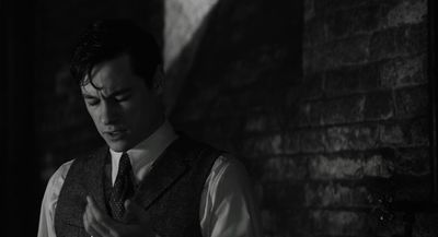 a man in a vest and tie standing in a dark room