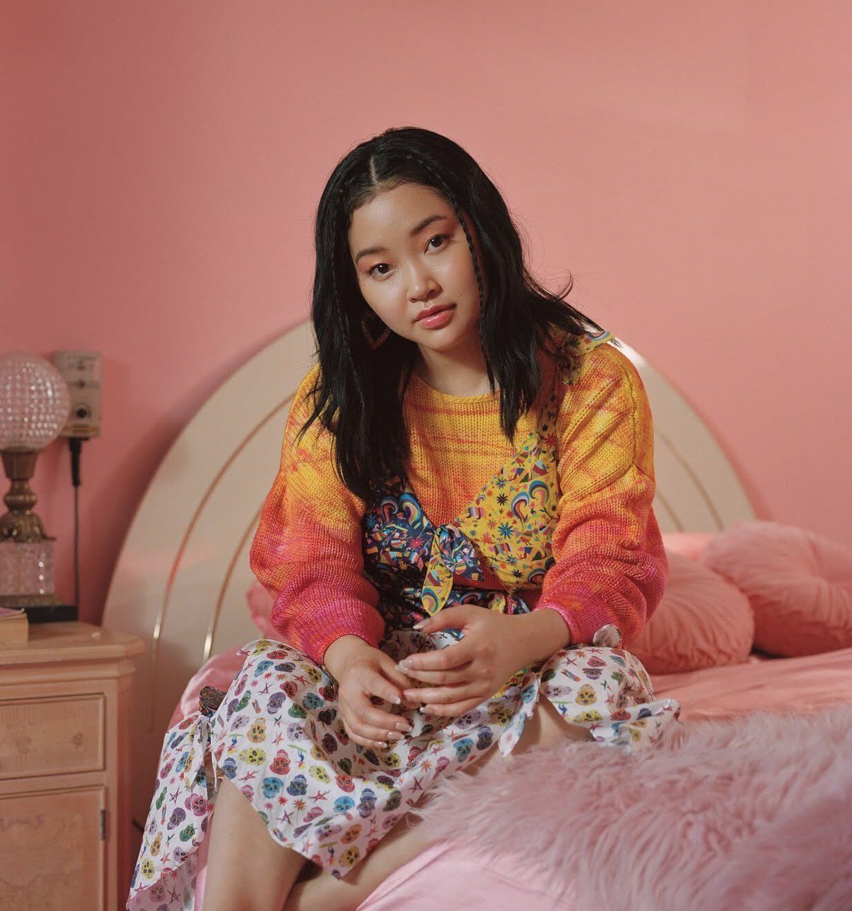 a girl sitting on a bed in a pink room