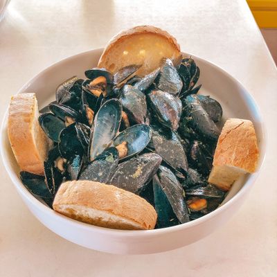 a bowl of mussels and bread on a table