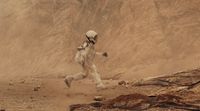 a man in a space suit running in the desert