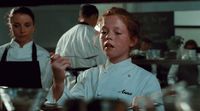 a woman in a chef's uniform standing in a kitchen