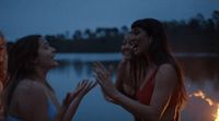 two women standing next to each other in front of a fire