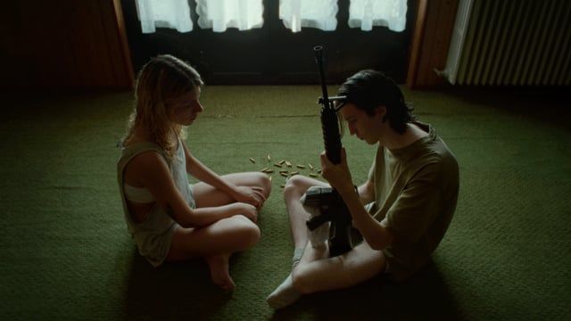a man and a woman sitting on the floor with a gun