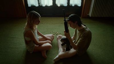 a man and a woman sitting on the floor with a gun