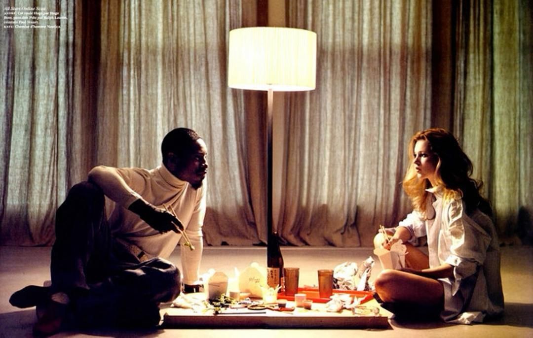 a man and a woman sitting on the floor in front of a lamp