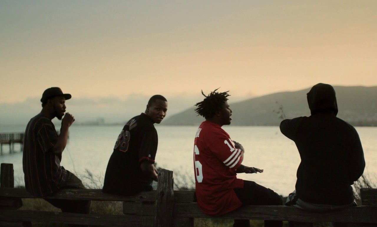a group of men sitting on top of a wooden bench