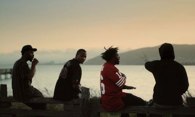 a group of men sitting on top of a wooden bench