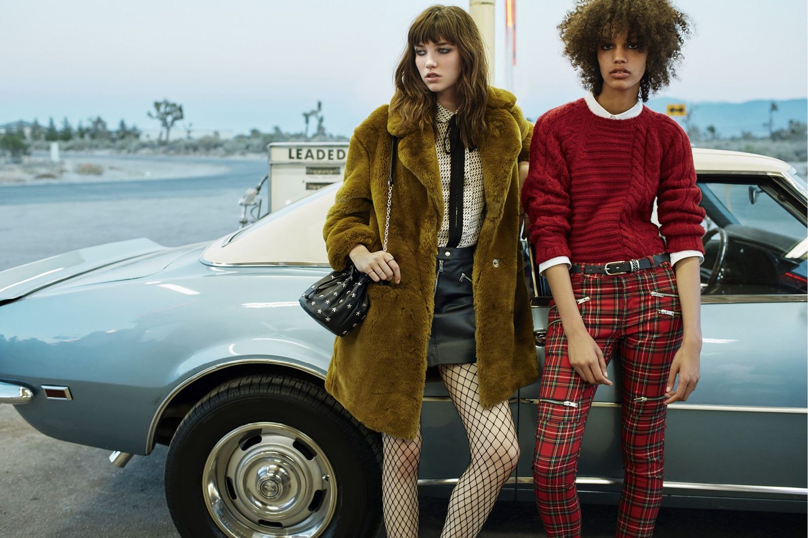 two women standing next to each other near a car
