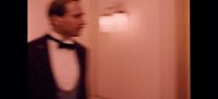 a man in a tuxedo standing in front of a door