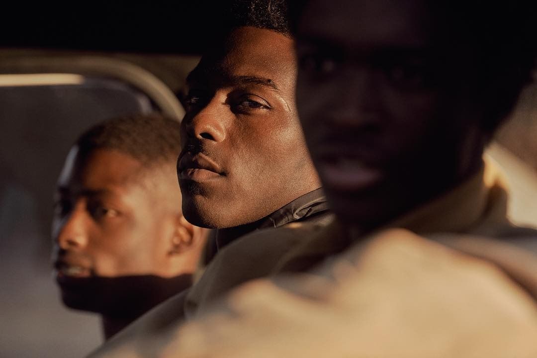 three men sitting in a car looking out the window