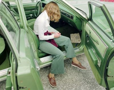 a woman sitting in the back of a green car