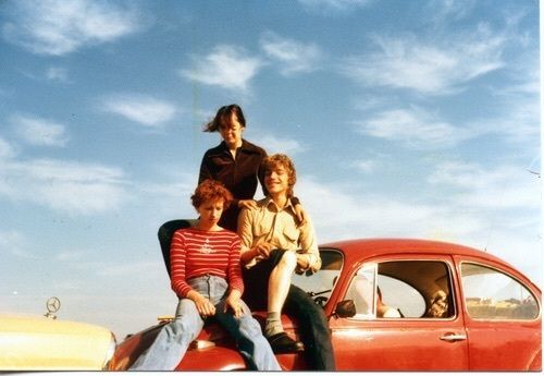 a group of people sitting on the hood of a car