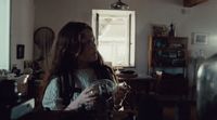 a woman standing in a kitchen holding a glass of wine