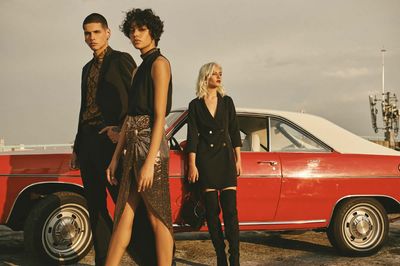 a group of people standing next to a red car
