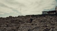 a person standing on a rocky hill with a building in the background