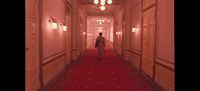 a person walking down a long hallway with red carpet