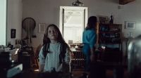 a young girl standing in a living room next to a window