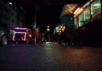 a street at night with a neon sign on the side of the road