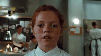 a woman with freckled hair standing in a kitchen