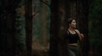 a woman in a black top is standing in the woods