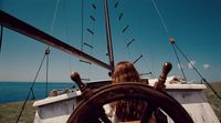 a woman sitting at the wheel of a boat