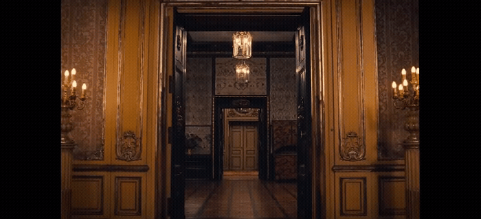 a hallway with a chandelier and a door leading to another room