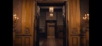 a hallway with a chandelier and a door leading to another room