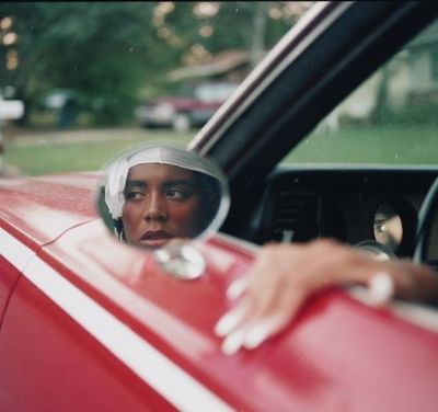 a woman sitting in a red car with a helmet on
