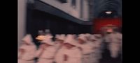 a group of people in white uniforms walking down a street