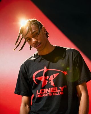 a man with dreadlocks standing in front of a red wall
