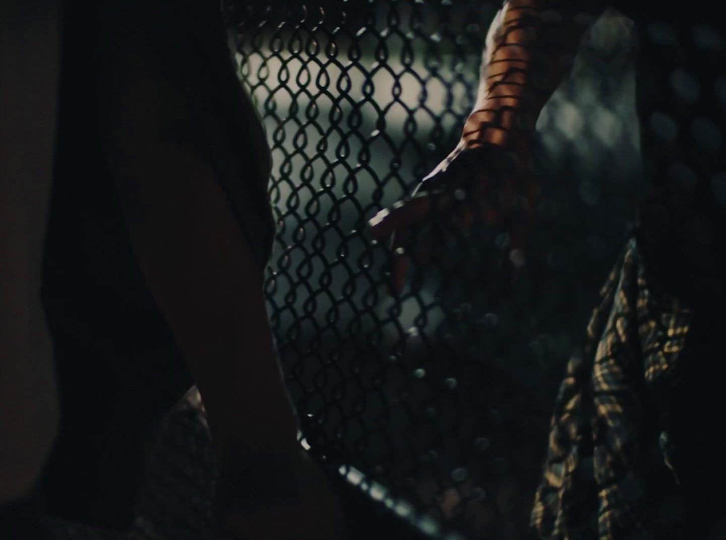 a person holding onto a chain link fence