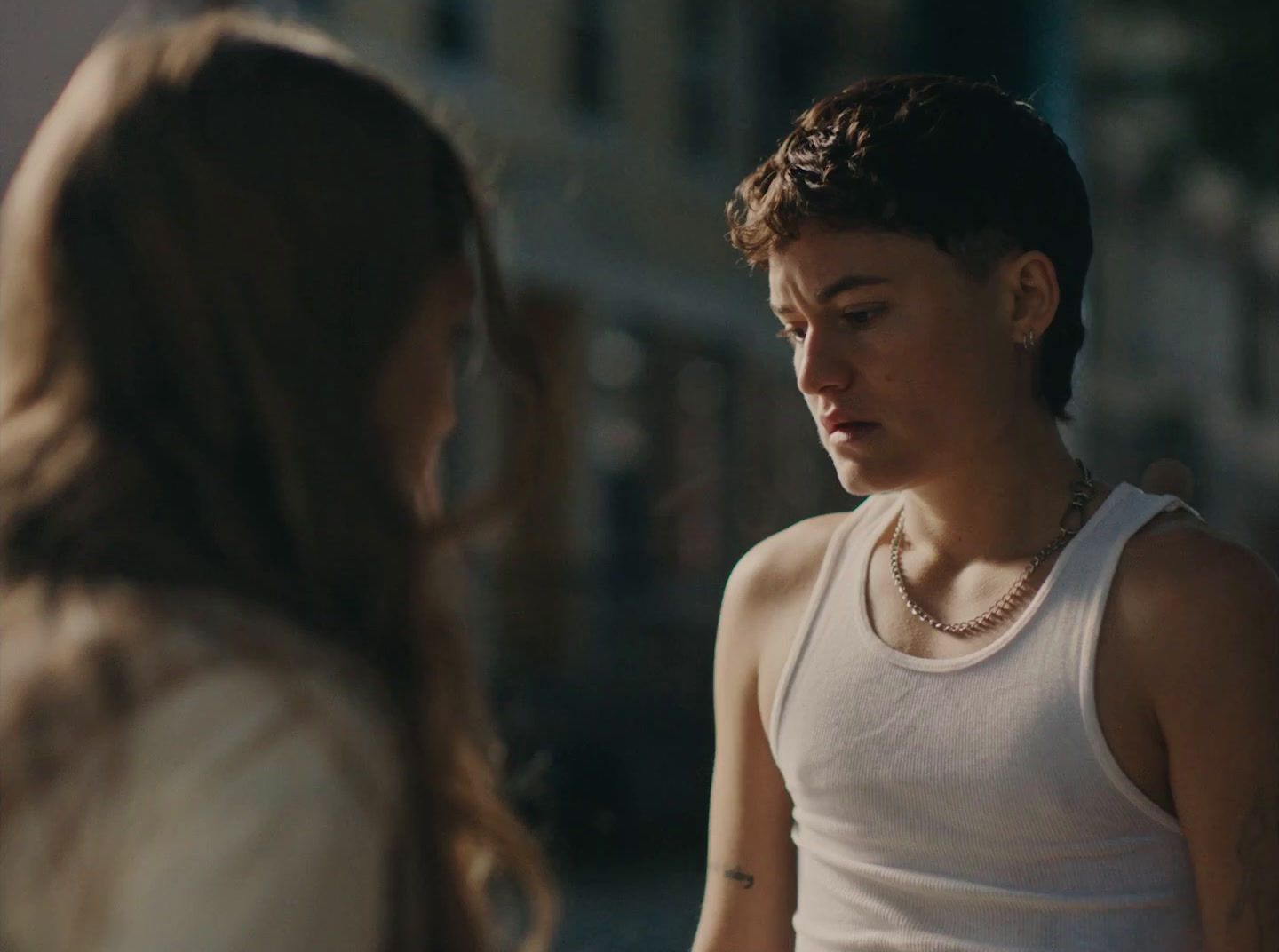 a woman standing next to a woman in a white tank top