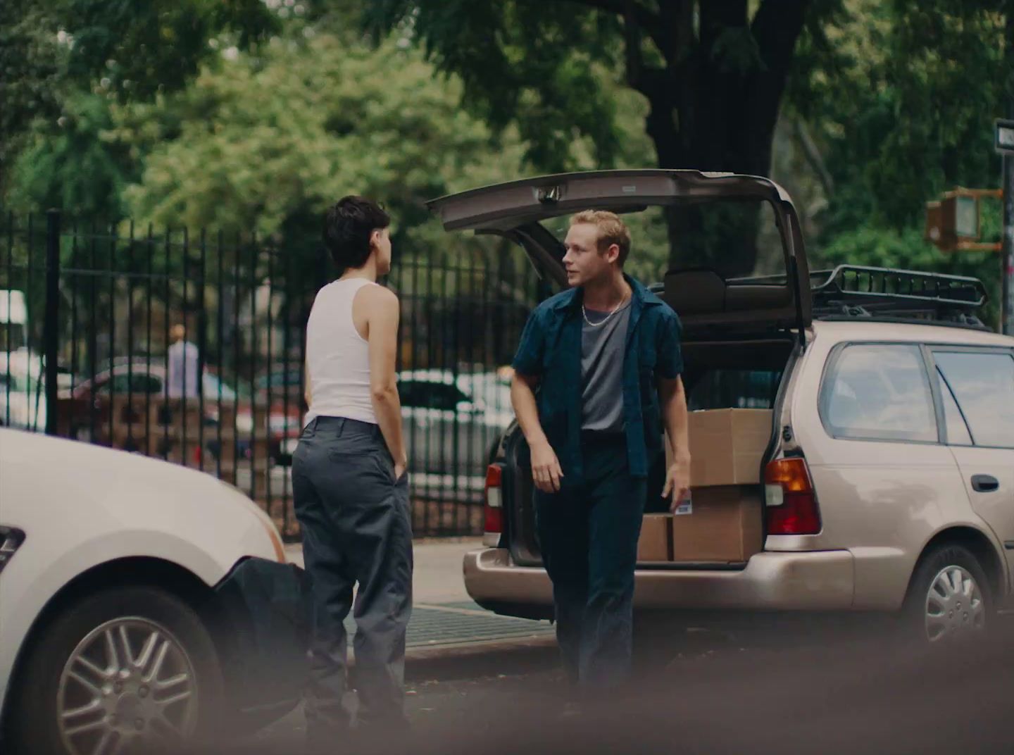 a man standing next to a woman in front of a car