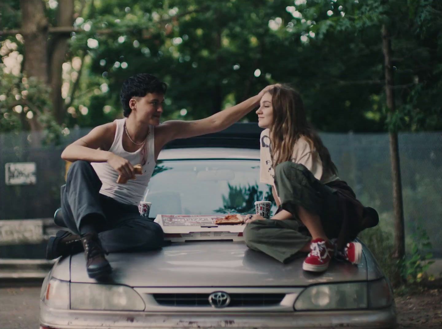 a man and a woman sitting on the hood of a car