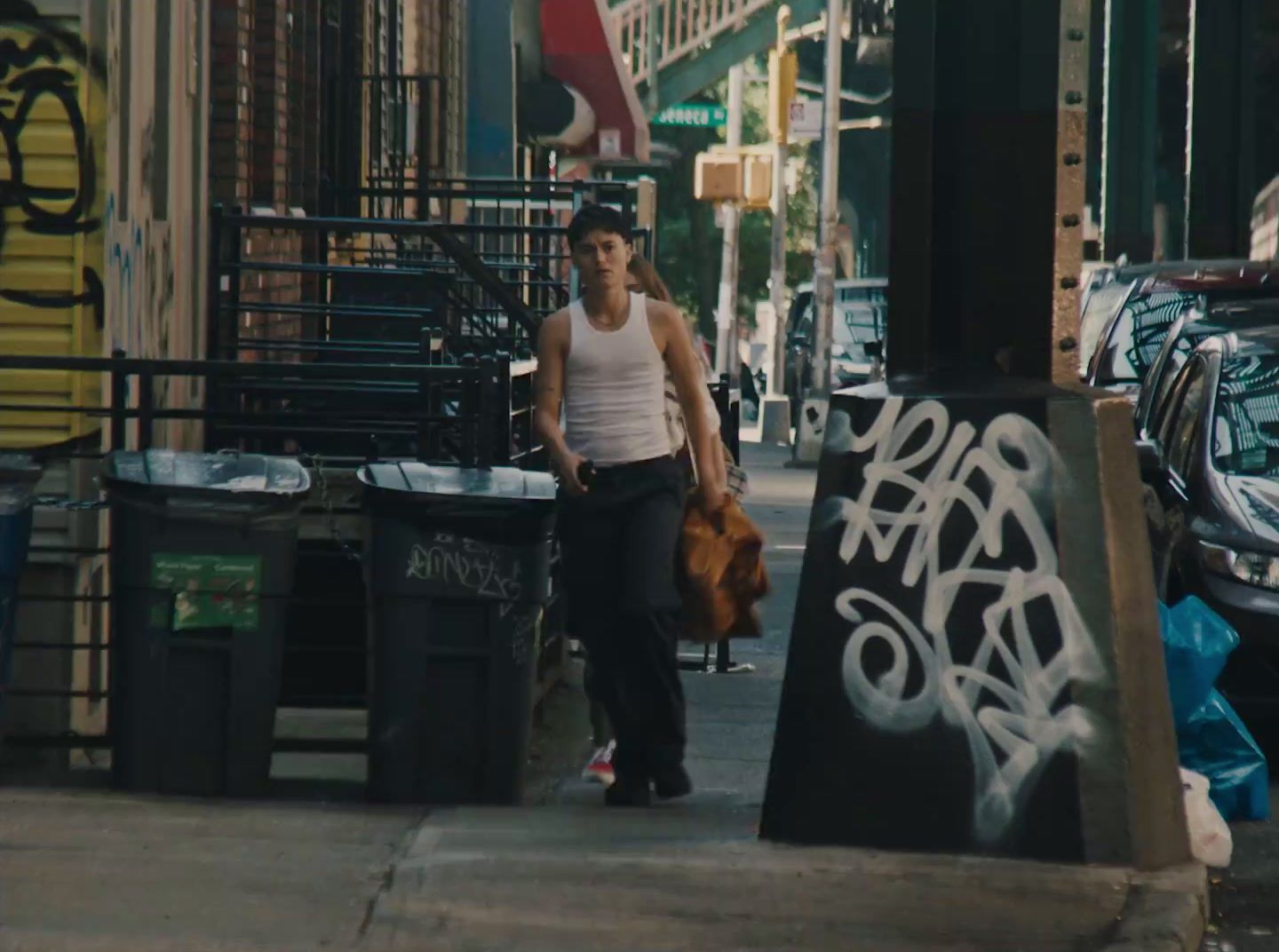 a man walking down a sidewalk next to a trash can